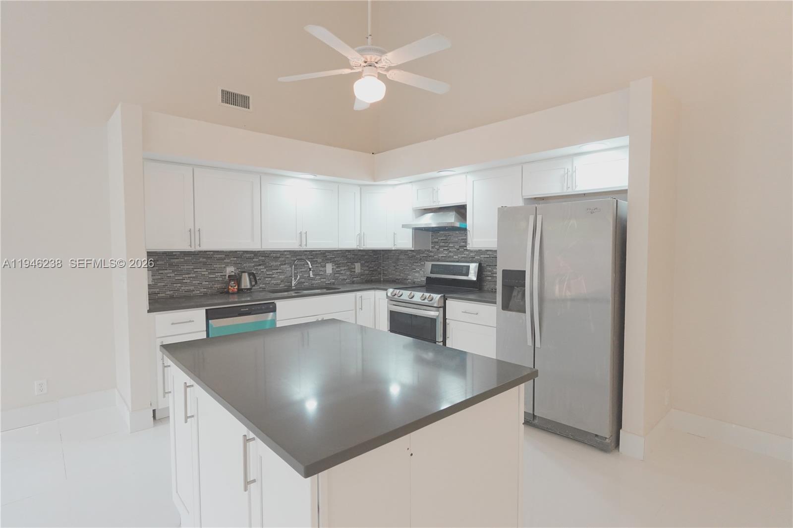 518 Northeast 48th Street, Unit 518 Boca Raton, FL 33431 - Photo 13 of 32 a kitchen with stainless steel appliances granite countertop a refrigerator a sink a stove and white cabinets with wooden floor