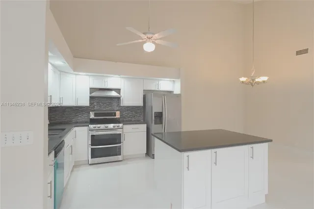 a kitchen with stainless steel appliances granite countertop a sink a stove a refrigerator with grey cabinets