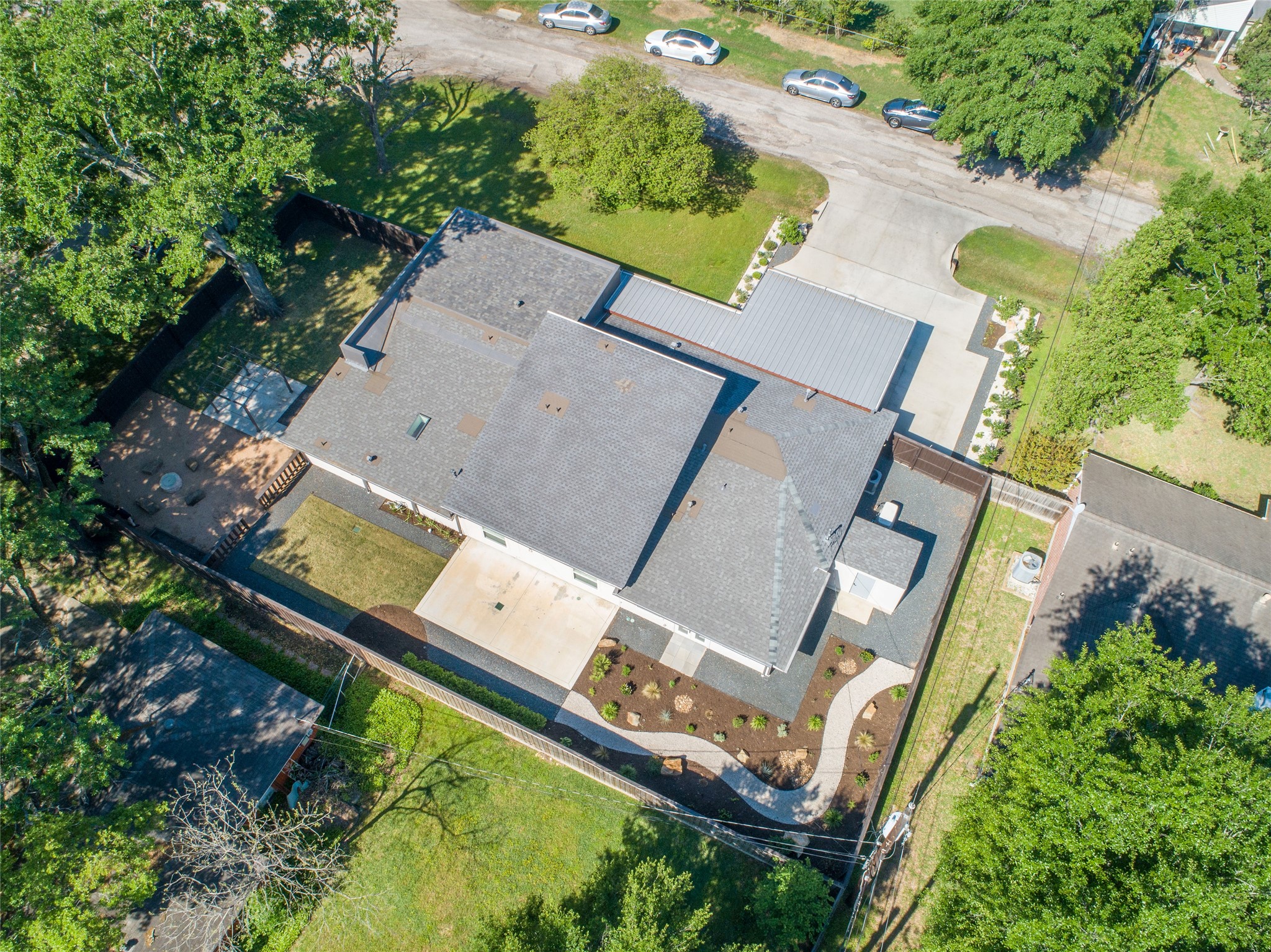 9400 Spring Branch Drive Houston, TX 77080 - Photo 44 of 45 Spacious single-story home with a modern roof design, surrounded by lush greenery and a well-maintained yard. Features a large driveway and a fenced backyard, perfect for outdoor activities.