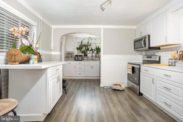 a kitchen with stainless steel appliances a microwave a stove a sink dishwasher and cabinets with wooden floor