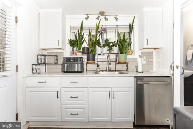 a kitchen with stainless steel appliances white cabinets and a window