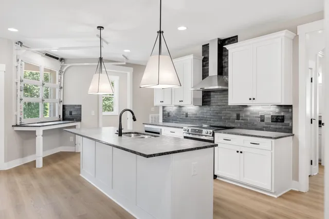 a kitchen with kitchen island granite countertop a sink a counter space appliances and a window