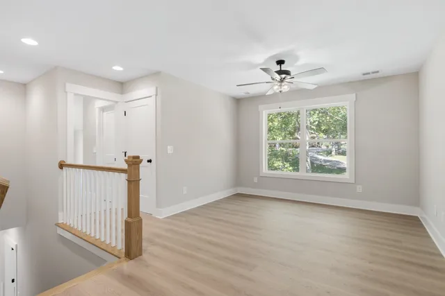 an empty room with wooden floor ceiling fan and windows