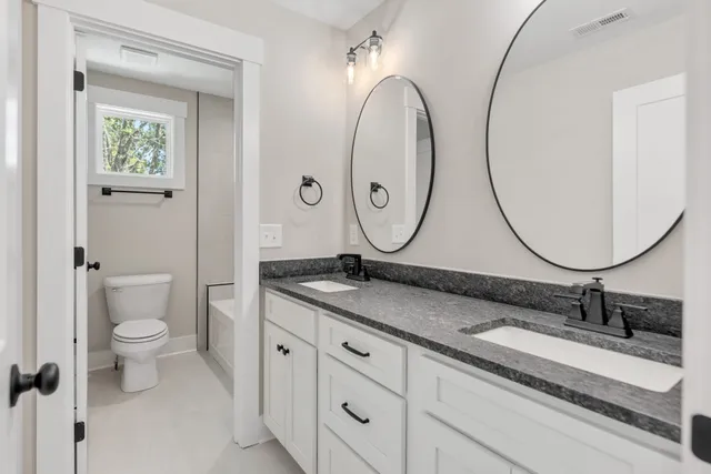 a bathroom with a granite countertop toilet a sink and a mirror