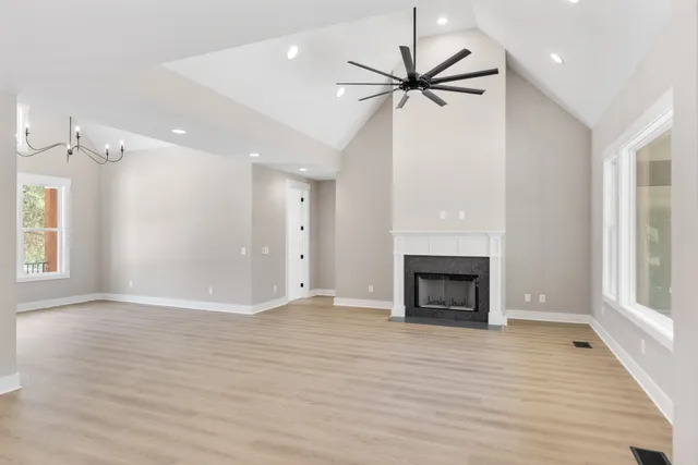 an empty room with wooden floor fireplace and windows