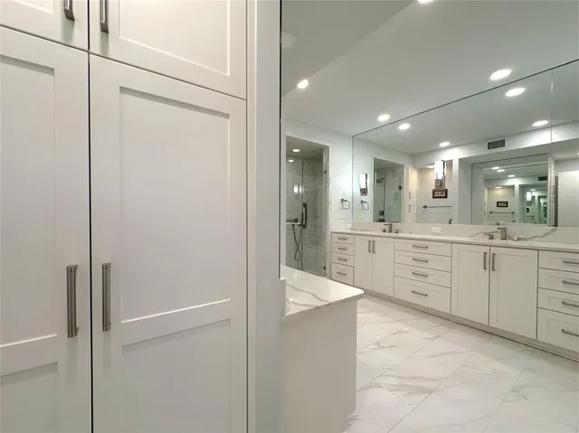 a large kitchen with a refrigerator a sink stainless steel appliances and cabinets