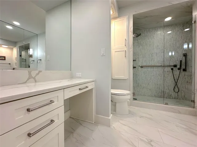 a bathroom with a shower sink vanity and toilet