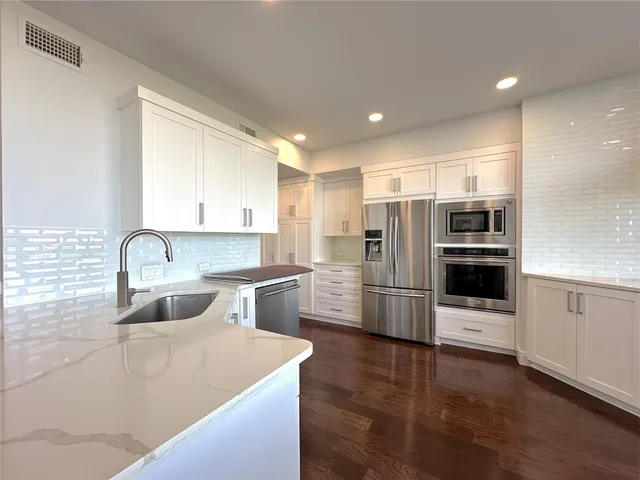 a kitchen with stainless steel appliances granite countertop a refrigerator and a stove top oven