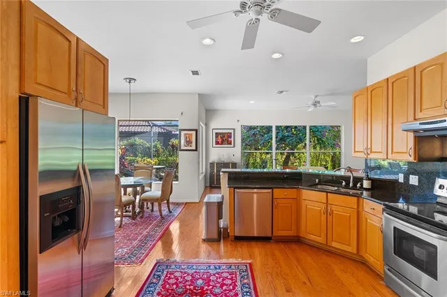 a kitchen with stainless steel appliances granite countertop a refrigerator a sink a stove and a wooden cabinets