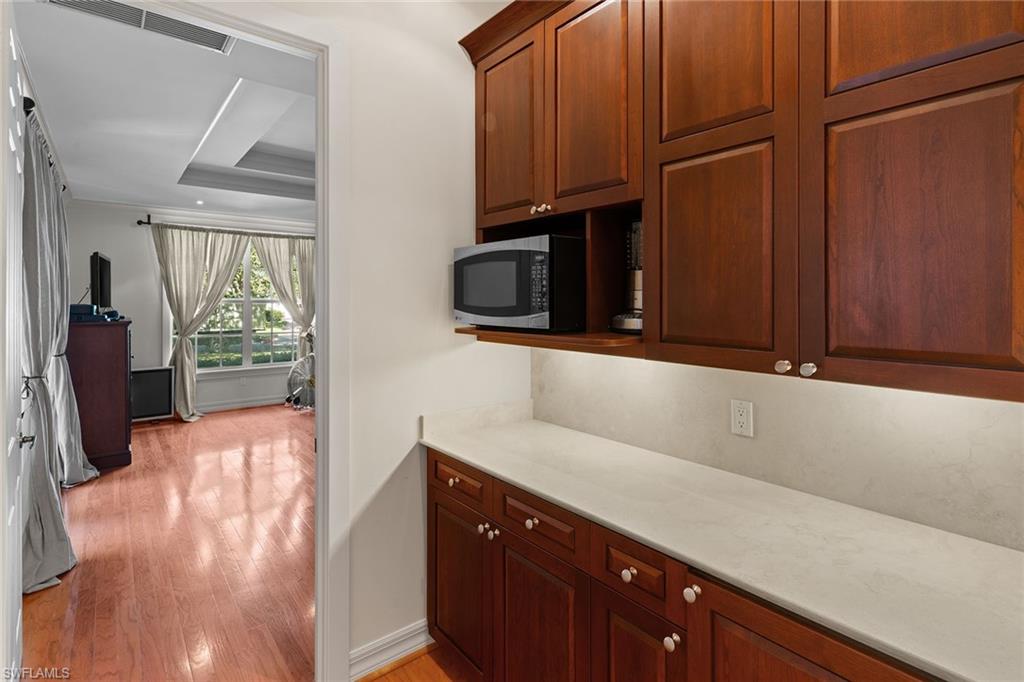 8840 Mariposa Court Naples, FL 34113 - Photo 19 of 50 a kitchen with wooden cabinets and a wooden floor
