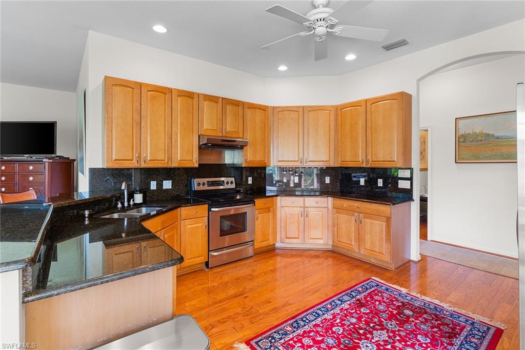 8840 Mariposa Court Naples, FL 34113 - Photo 33 of 50 a kitchen with stainless steel appliances granite countertop a stove a sink and a microwave