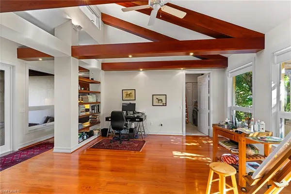 a bedroom with a bed wooden floor and large window