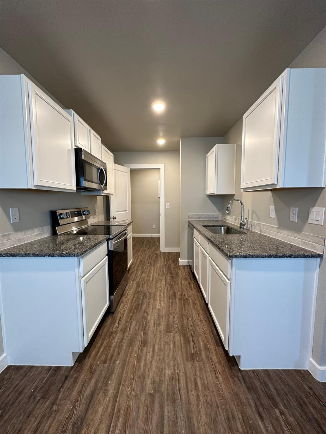 1604 135th Street Lubbock, TX 79423 - Photo 5 of 15 a kitchen with granite countertop wooden floors a stove and a sink