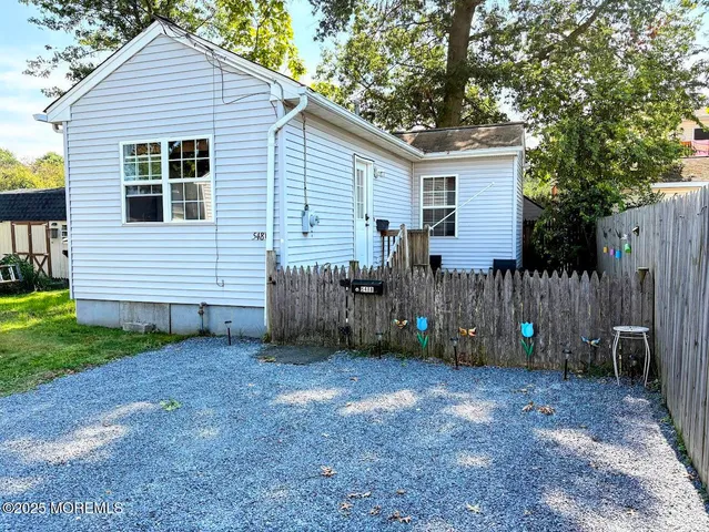 a view of a house with a yard and a large tree