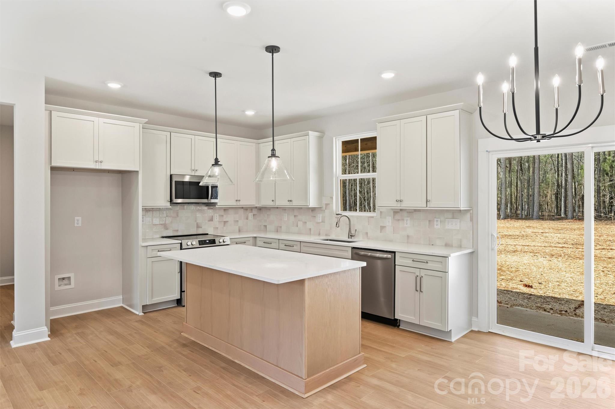 a kitchen with stainless steel appliances granite countertop a stove a sink a refrigerator and white cabinets with wooden floor