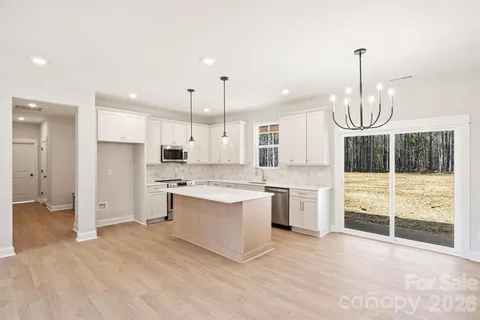 a large kitchen with granite countertop a stove a sink and a refrigerator