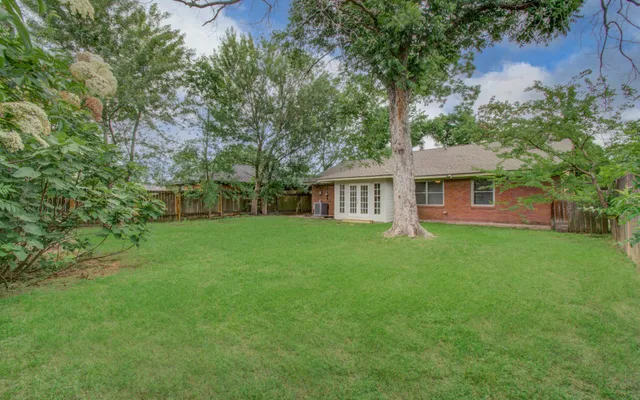 a view of a house with backyard and a tree