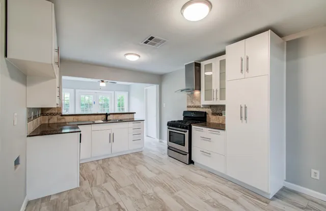 a kitchen with granite countertop a refrigerator stove top oven and sink