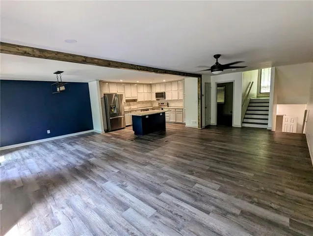 a large room with kitchen island stainless steel appliances wooden floor and living room view