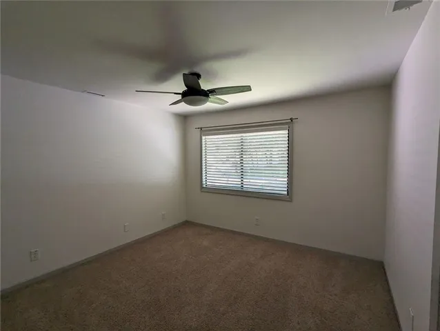 an empty room with a window and a fan