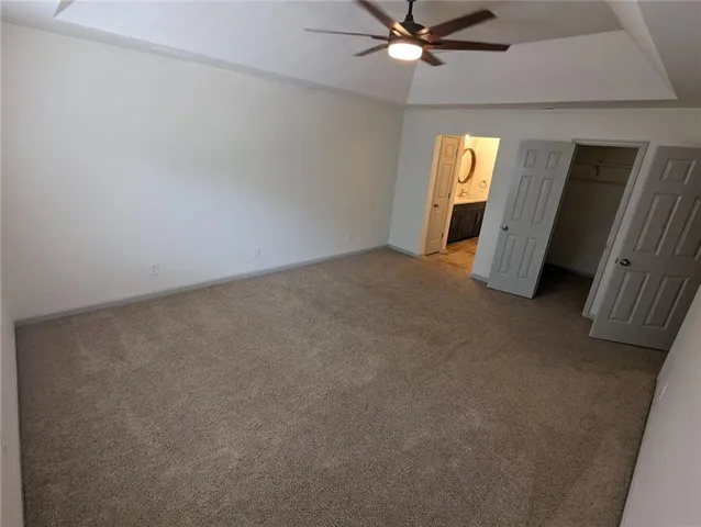 an empty room with chandelier fan and windows