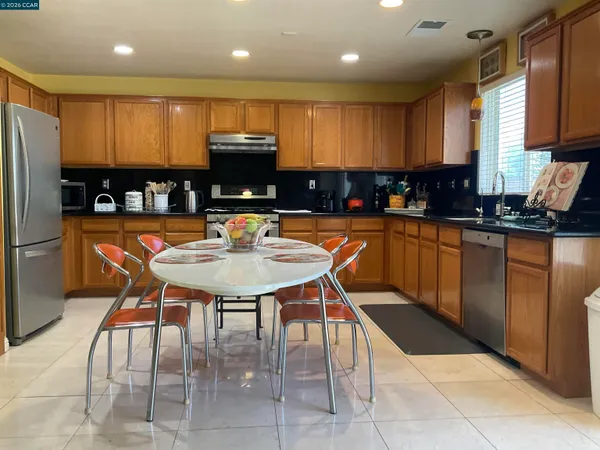 a kitchen with stainless steel appliances granite countertop a table chairs sink refrigerator and microwave