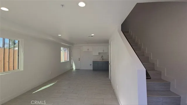 a view of empty room with kitchen and window