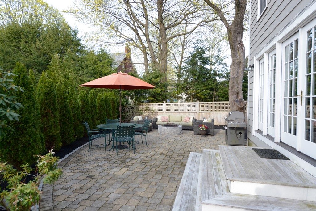 5 Ingraham Road Wellesley, MA 02482 - Photo 11 of 11 a view of a patio with table and chairs under an umbrella with large trees