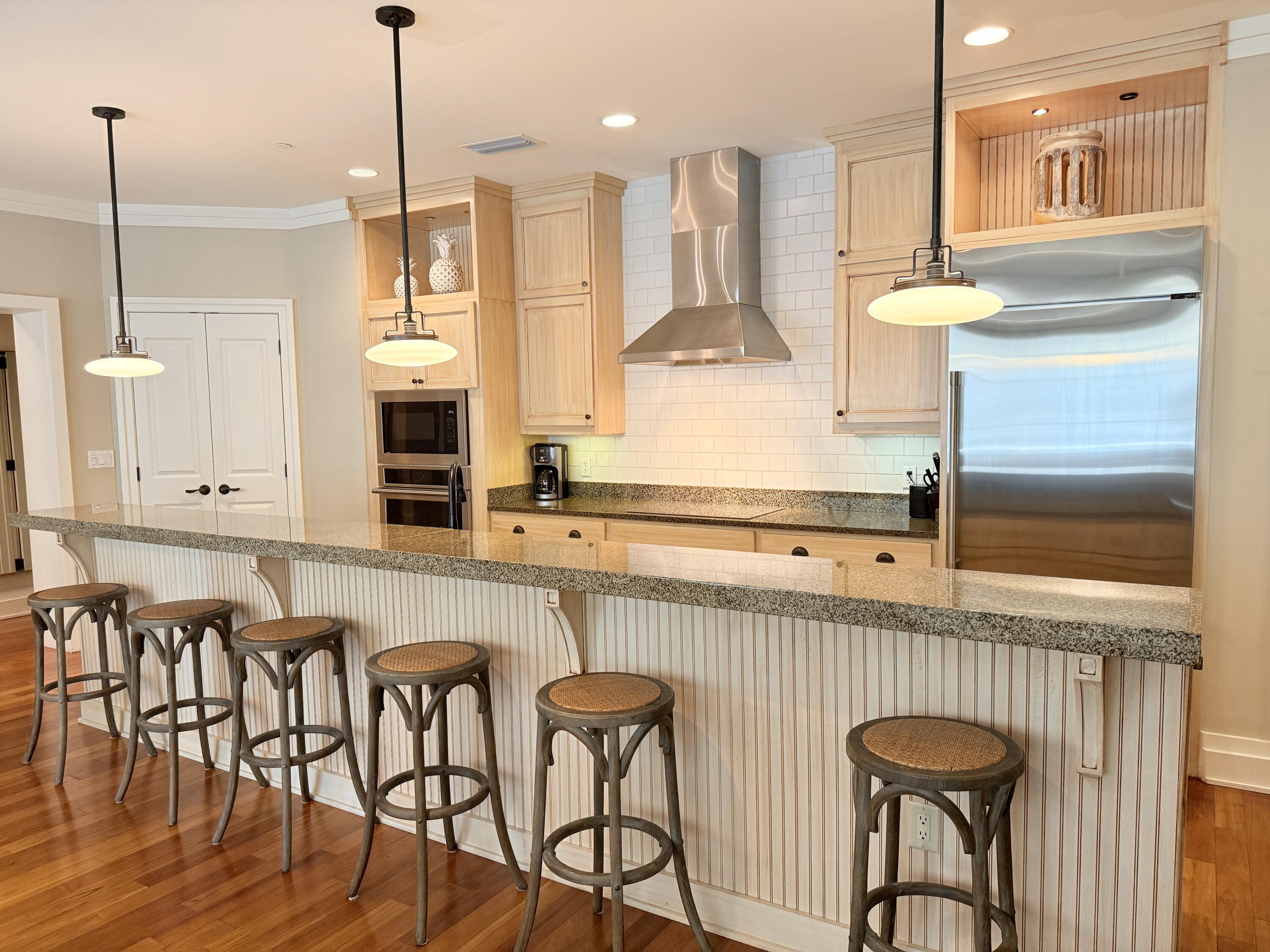 32461 East County Highway 30A, Unit 104 Inlet Beach, FL 32461 - Photo 20 of 97 a kitchen with stainless steel appliances granite countertop a stove a sink a oven a dining table and chairs with wooden floor