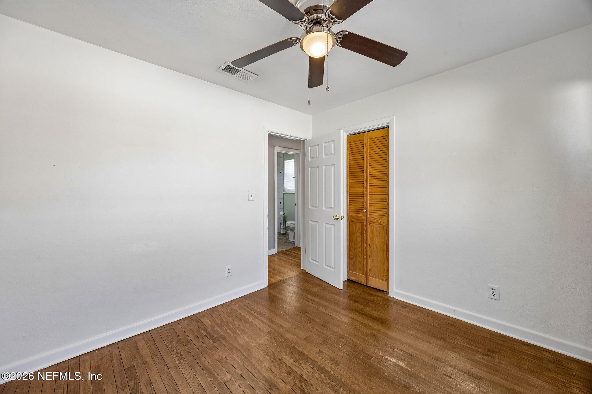 3647 Coronado Road Jacksonville, FL 32217 - Photo 33 of 49 an empty room with wooden floor chandelier fan and closet area