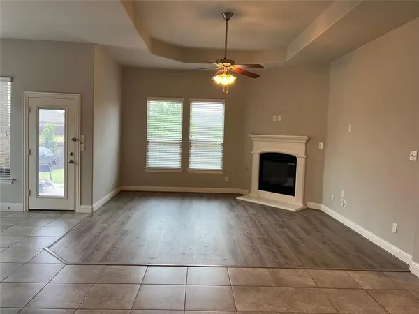 a view of an empty room with window and chandelier fan
