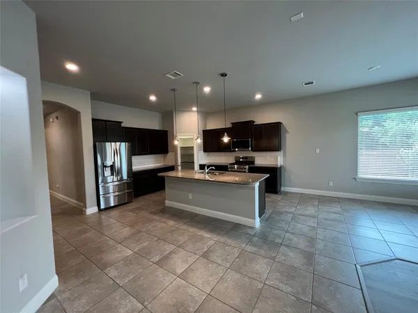 a large kitchen with stainless steel appliances kitchen island granite countertop a refrigerator and a stove top oven