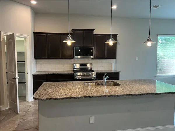 a kitchen with kitchen island granite countertop a sink a counter top space appliances and cabinets