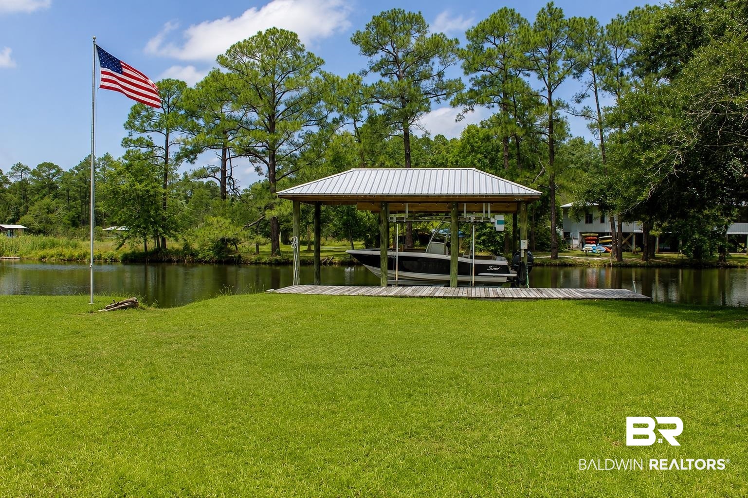 9825 Wolf Creek Ridge Elberta, AL 36530 - Photo 64 of 76 Expansive green lawn with a covered boat dock featuring a metal roof and a wooden pier