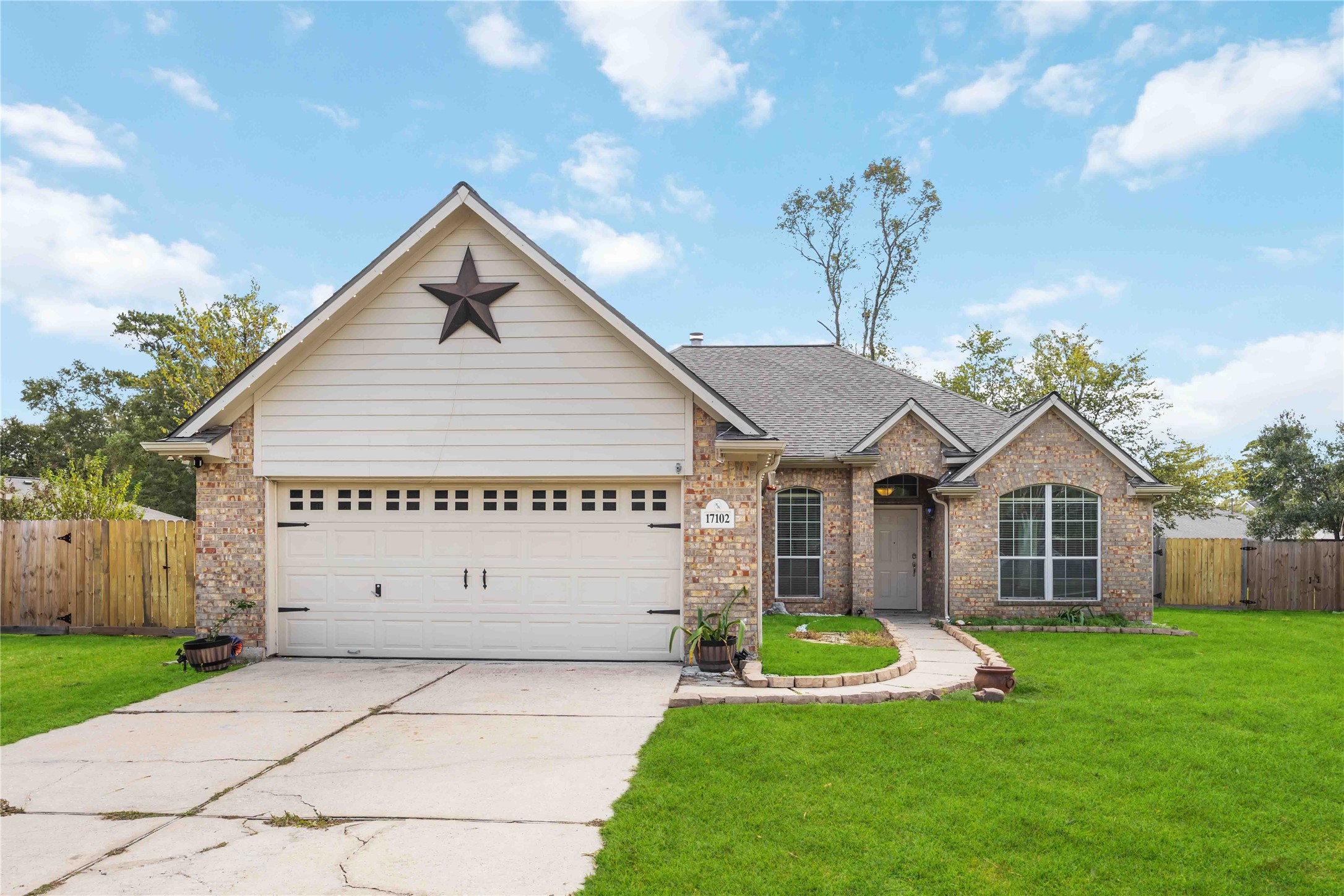Charming single-story brick home with a gabled roof, featuring a two-car garage adorned with a decorative star.