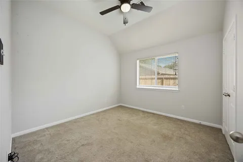 an empty room with a chandelier fan and windows