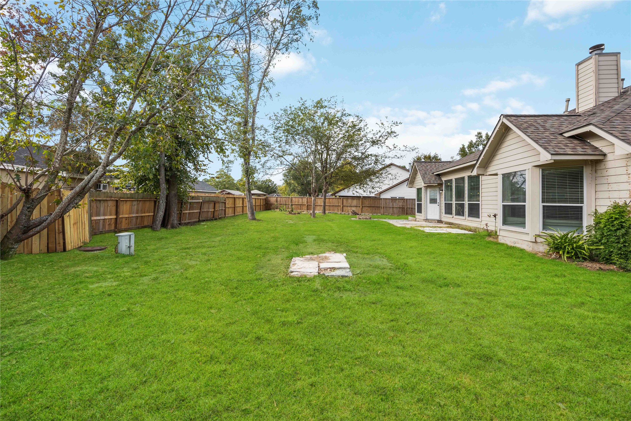 17102 Jetty Court Crosby, TX 77532 - Photo 36 of 39 Spacious backyard with lush green lawn, mature trees, and a wooden fence for privacy.