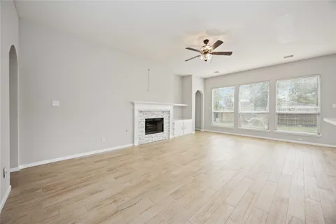 an empty room with wooden floor fan and windows