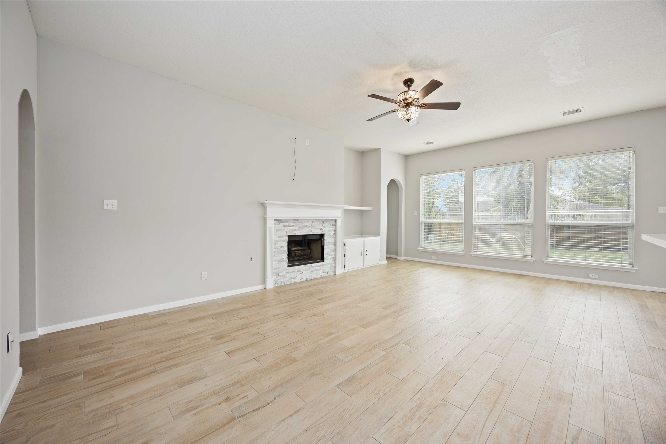 17102 Jetty Court Crosby, TX 77532 - Photo 9 of 39 Spacious living room features light wood flooring, a cozy fireplace, and ample natural light from large windows.