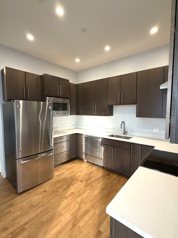 13 West Central Street, Unit 2 Natick, MA 01760 - Photo 2 of 14 a kitchen with stainless steel appliances kitchen island granite countertop a refrigerator a sink a stove a microwave and wooden cabinets