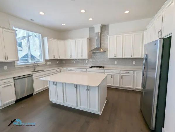 a kitchen that has a lot of white cabinets and stainless steel appliances