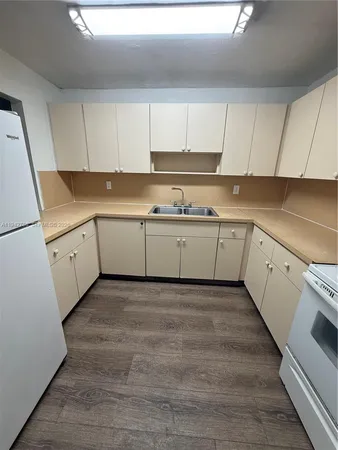 a kitchen with granite countertop white cabinets and white appliances