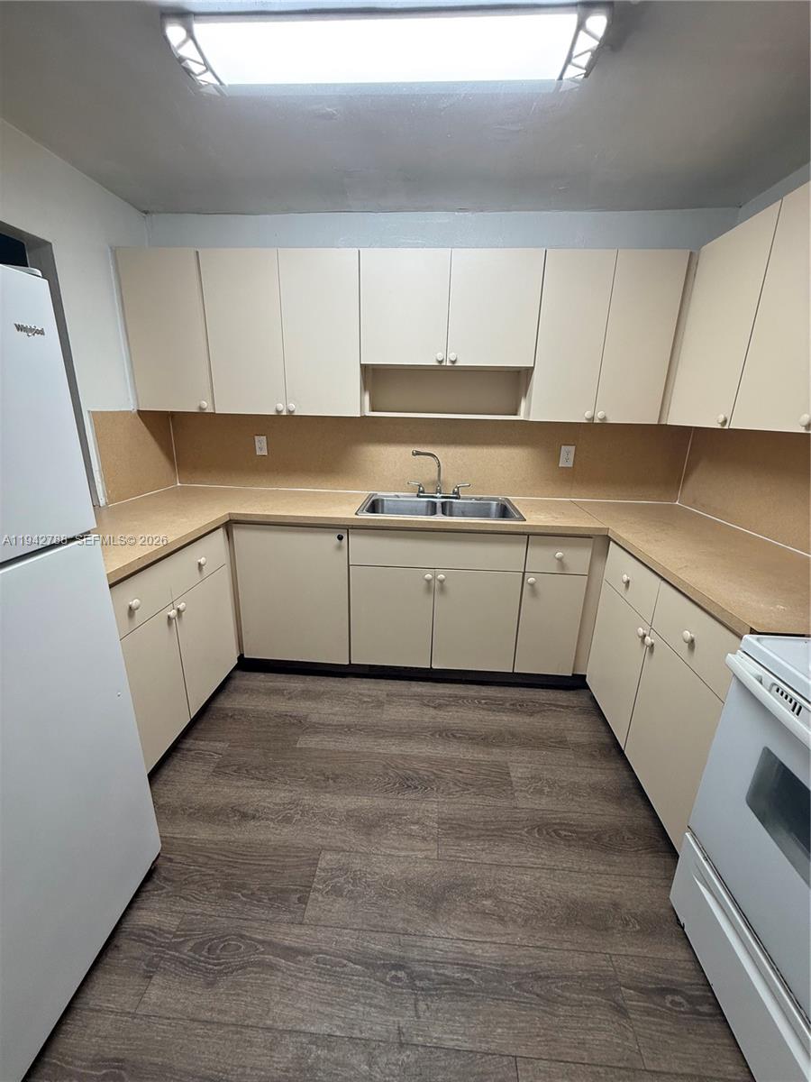 1085 West 68th Street, Unit 309 Hialeah, FL 33014 - Photo 8 of 9 a kitchen with granite countertop white cabinets and white appliances