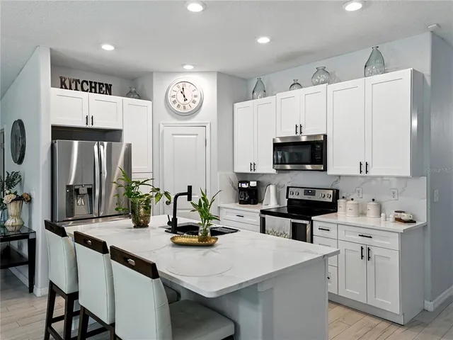 a kitchen with stainless steel appliances a sink a stove a refrigerator cabinets and dining table