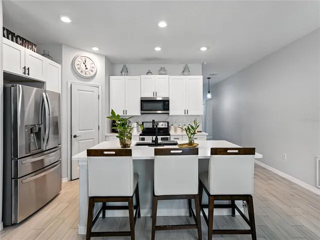 a kitchen with a table chairs refrigerator and microwave