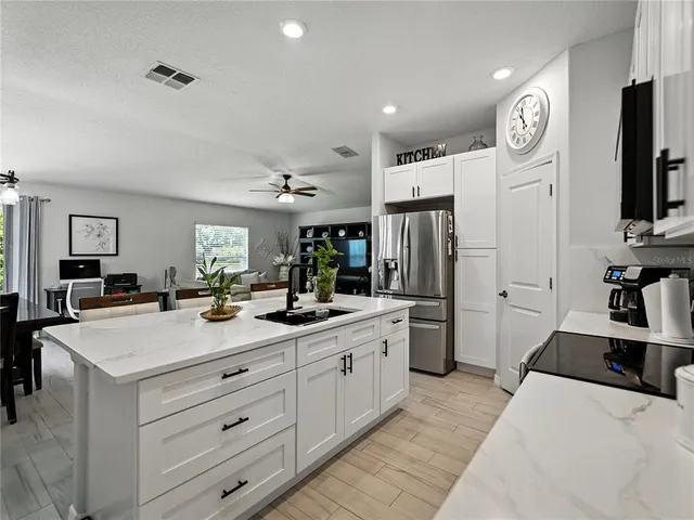 a large kitchen with a refrigerator a stove a sink a dining table and chairs with wooden floor