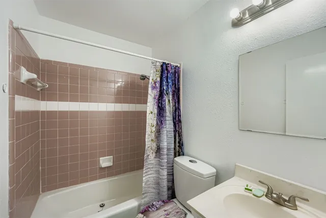 a bathroom with a shower a sink and toilet