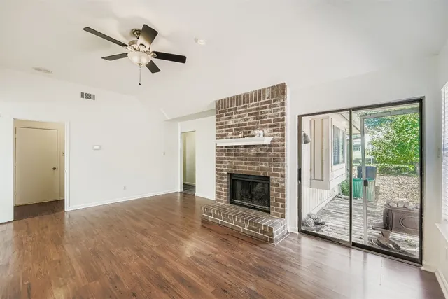 a view of an empty room with wooden floor fireplace and a window