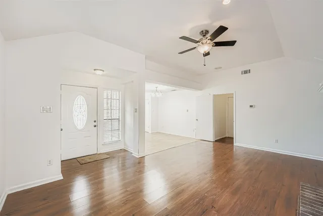an empty room with wooden floor and windows