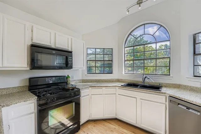 a kitchen with granite countertop a stove a sink and a microwave